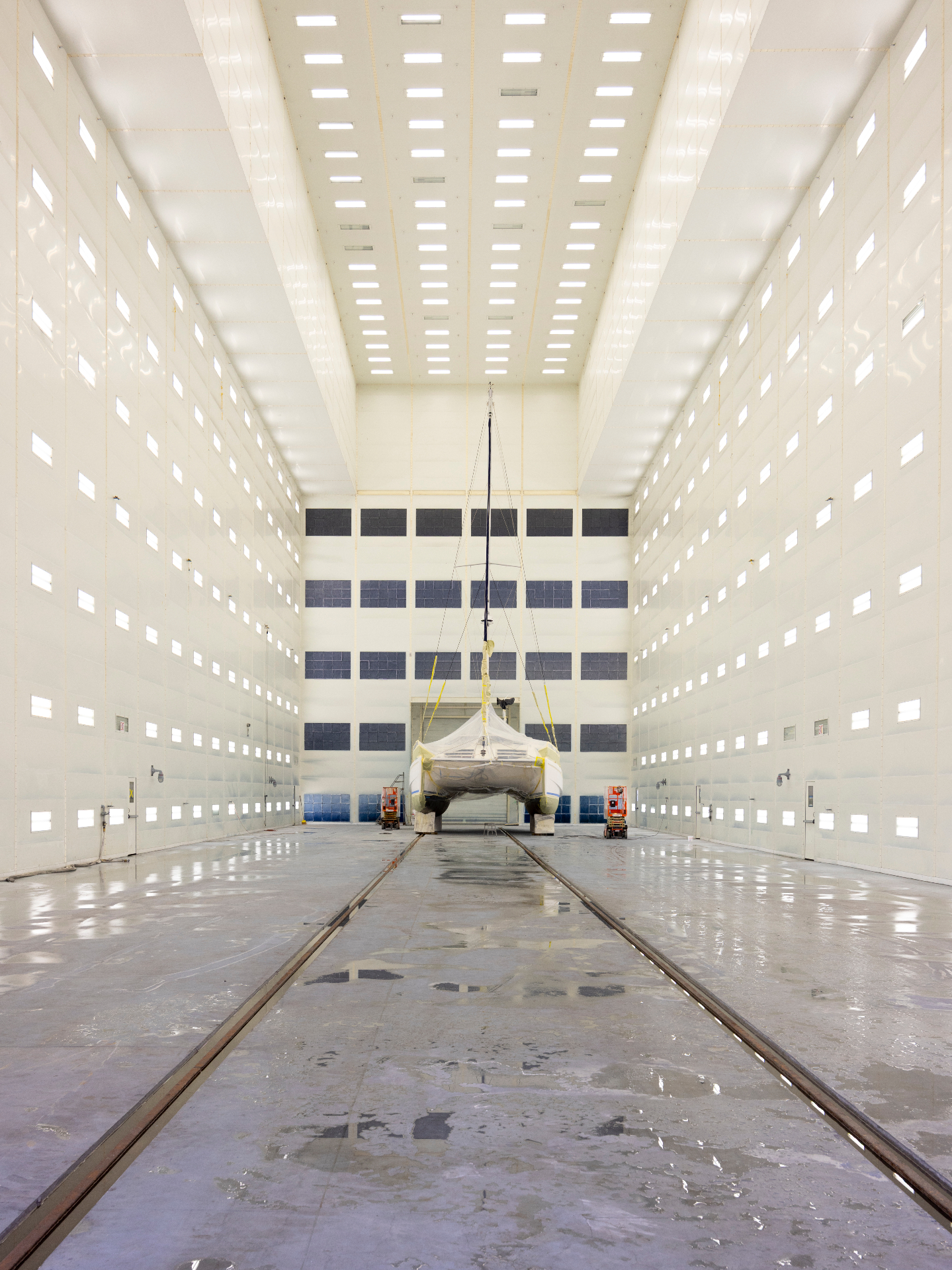Catamaran positioned inside a large enclosed paint and refit facility.